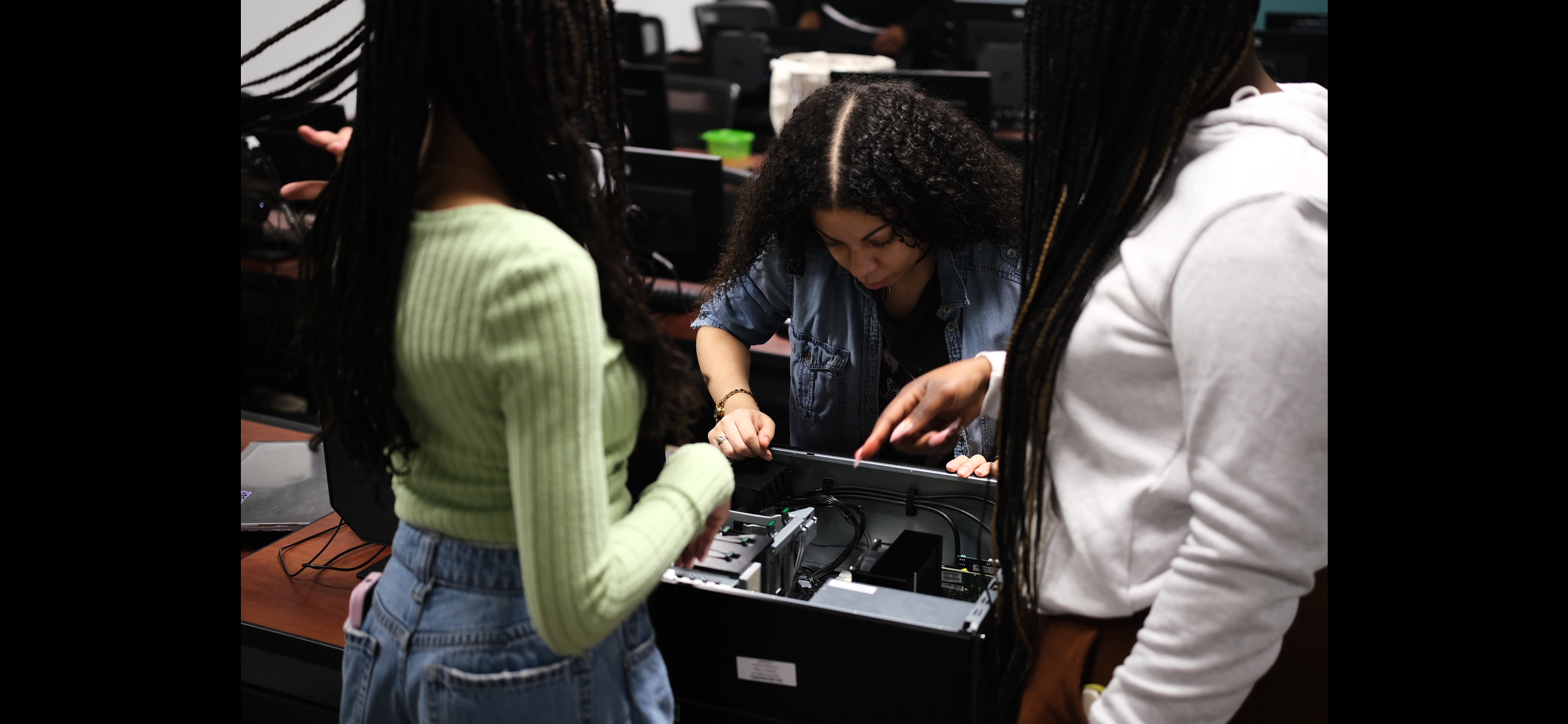 Three students installing a RAM stick